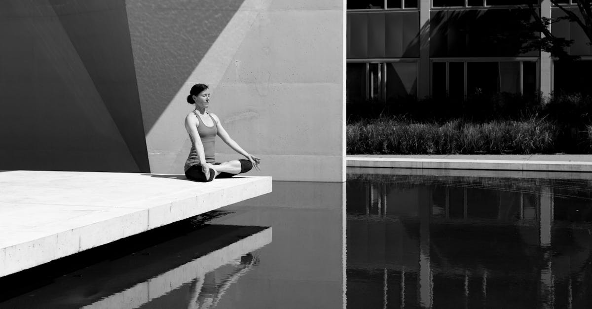 A woman meditating by a poolside, reflecting tranquility and focus in a minimalist setting.