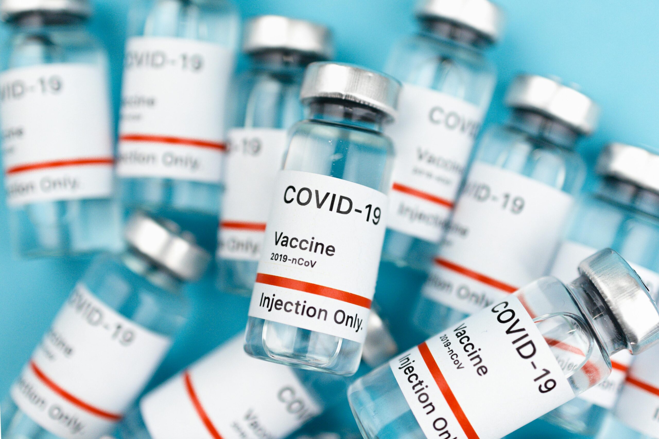 Close-up of COVID-19 vaccine vials labeled for injection only, against a blue background.
