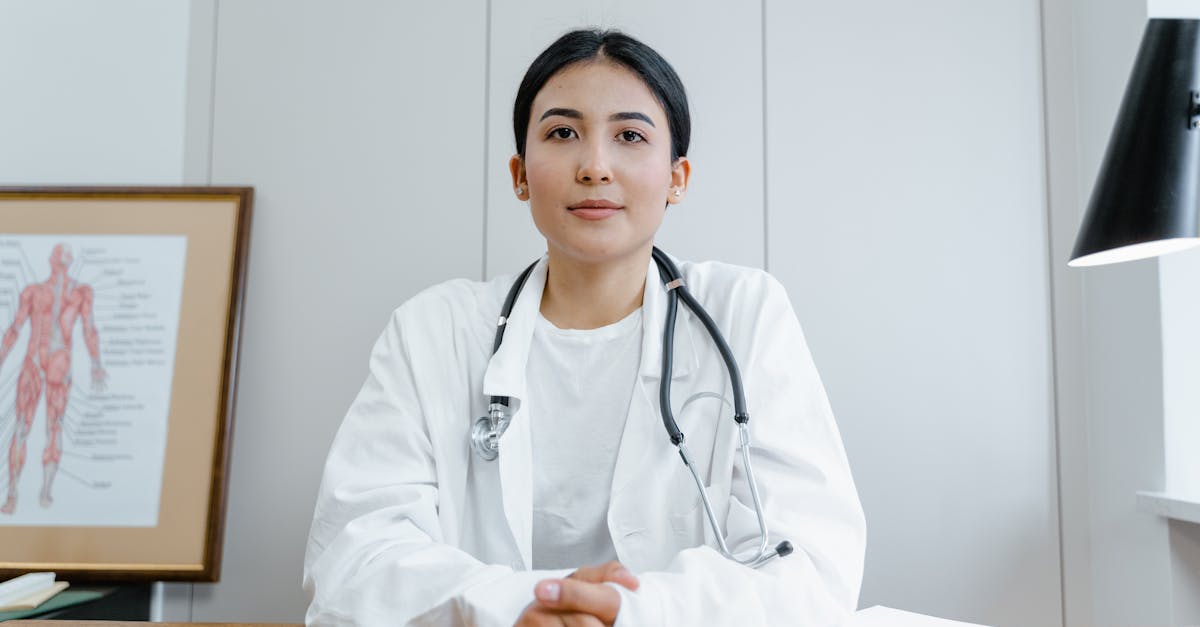 Young female doctor sitting at desk with stethoscope, ready for telehealth consultation.