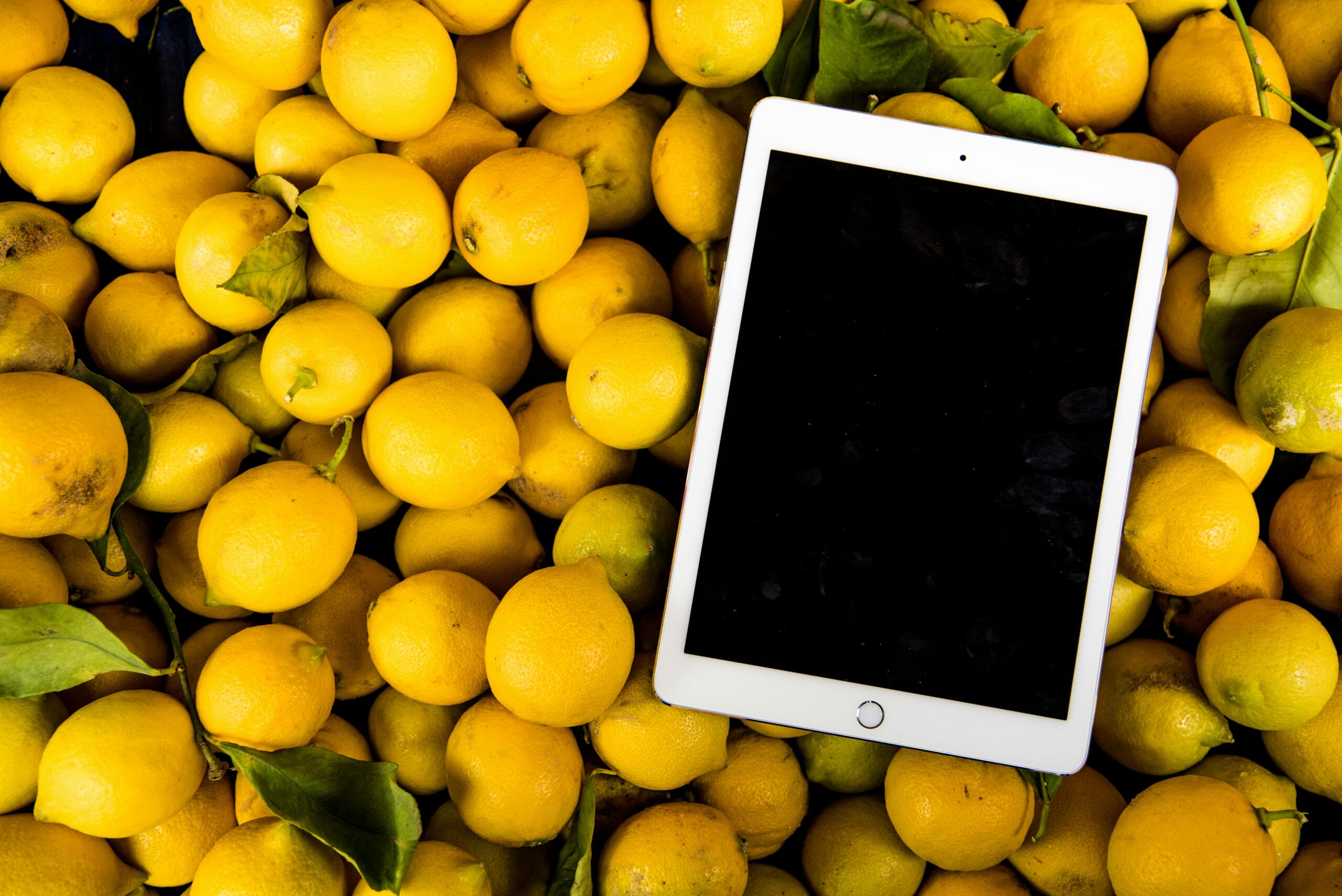 A bright, fresh collection of lemons with a blank tablet screen for copyspace.