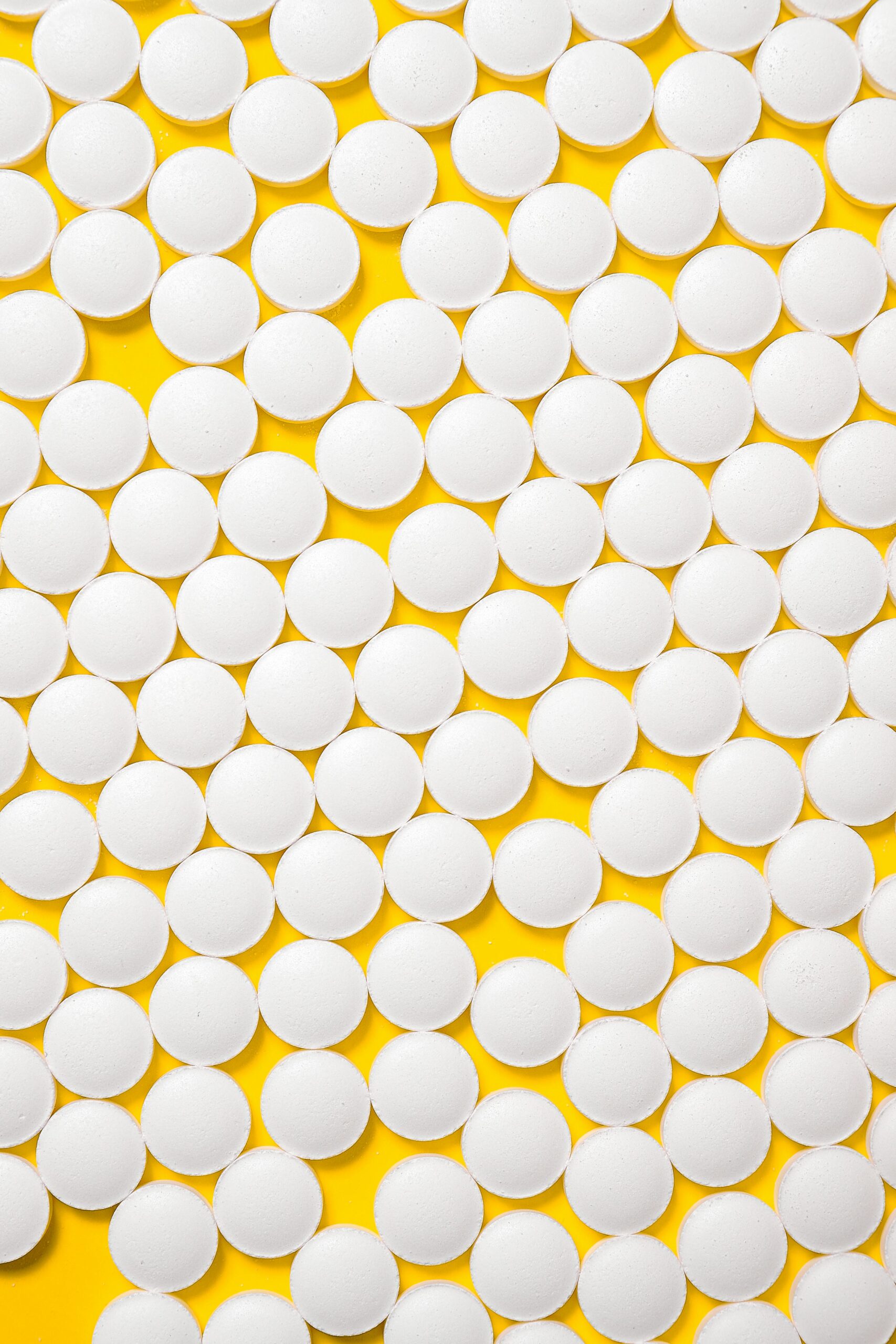 White round pills on a vibrant yellow background showcasing a pharmaceutical theme.
